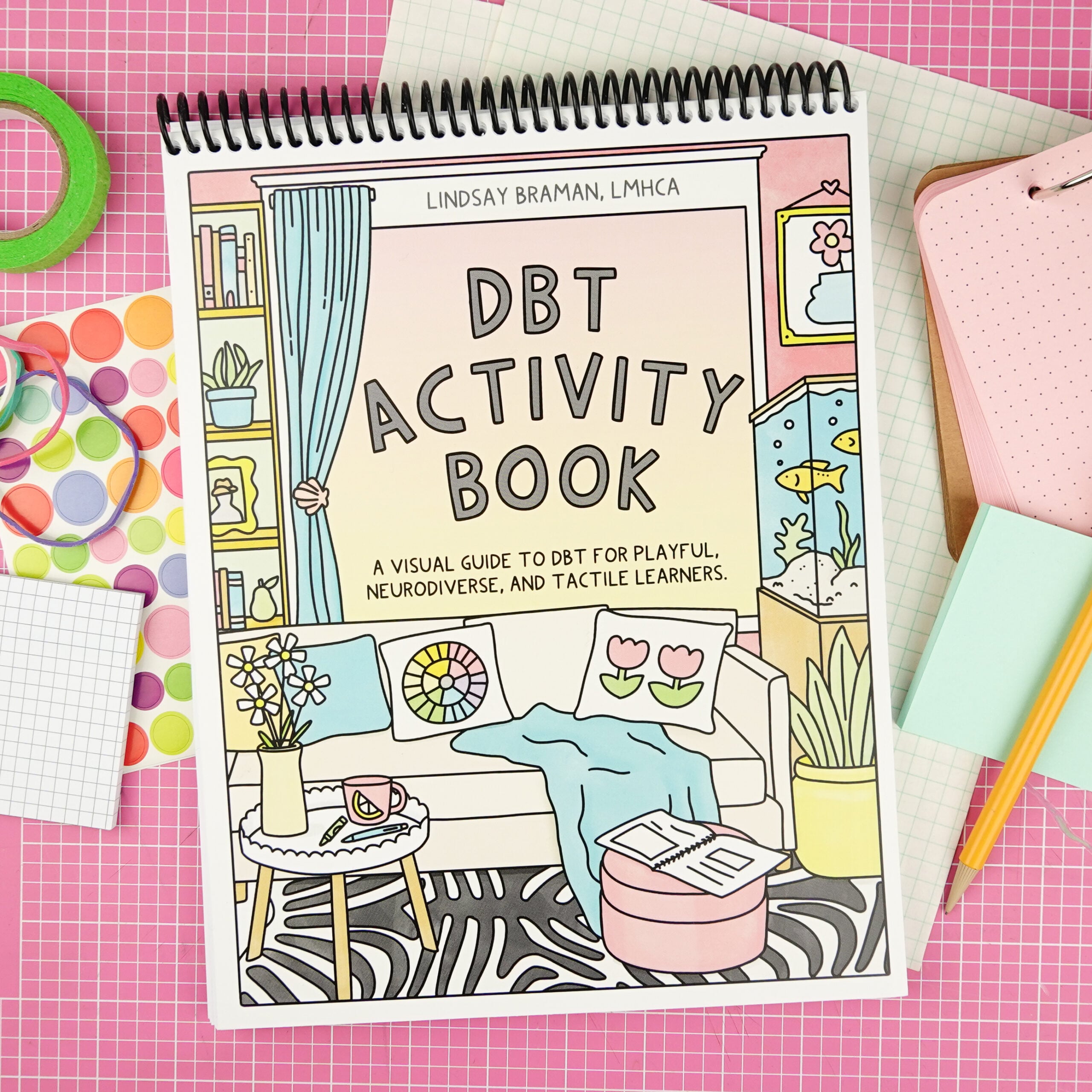 The dbt activity book on a pink grid cutting mat