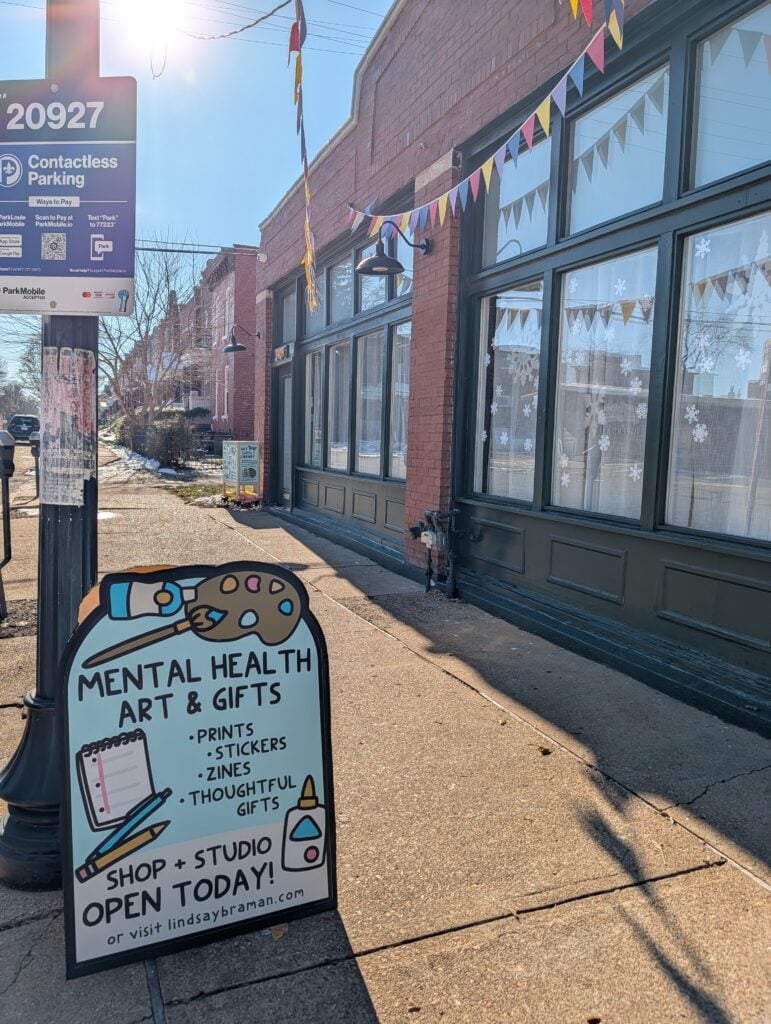 A sandwich board on the sidewalk in front of lindsay braman studios